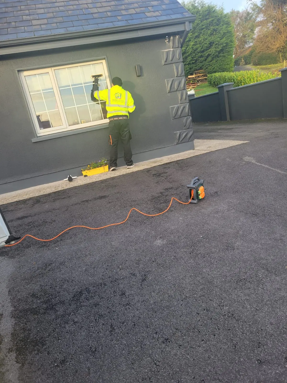 Window cleaning on a modern grey rendered house with power tools