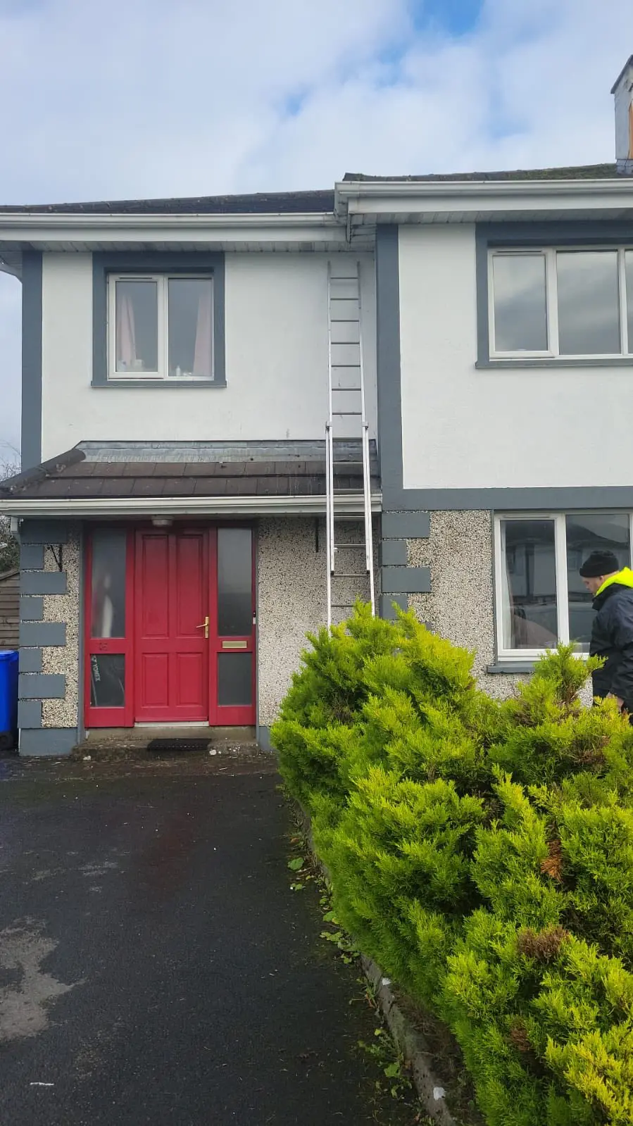 Gutter and roof inspection on a residential semi-detached house with a red front door